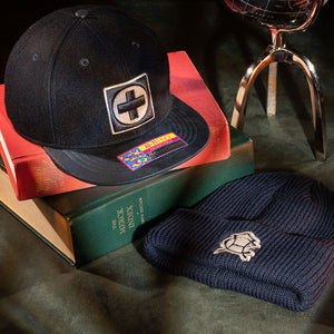 Cruz Azul Prep Snapback and Club America Ivy Beanie laying on books with an atlas in the background.