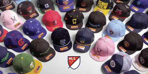 Collection of various MLS club hats with on a white background, featuring MLS logo.