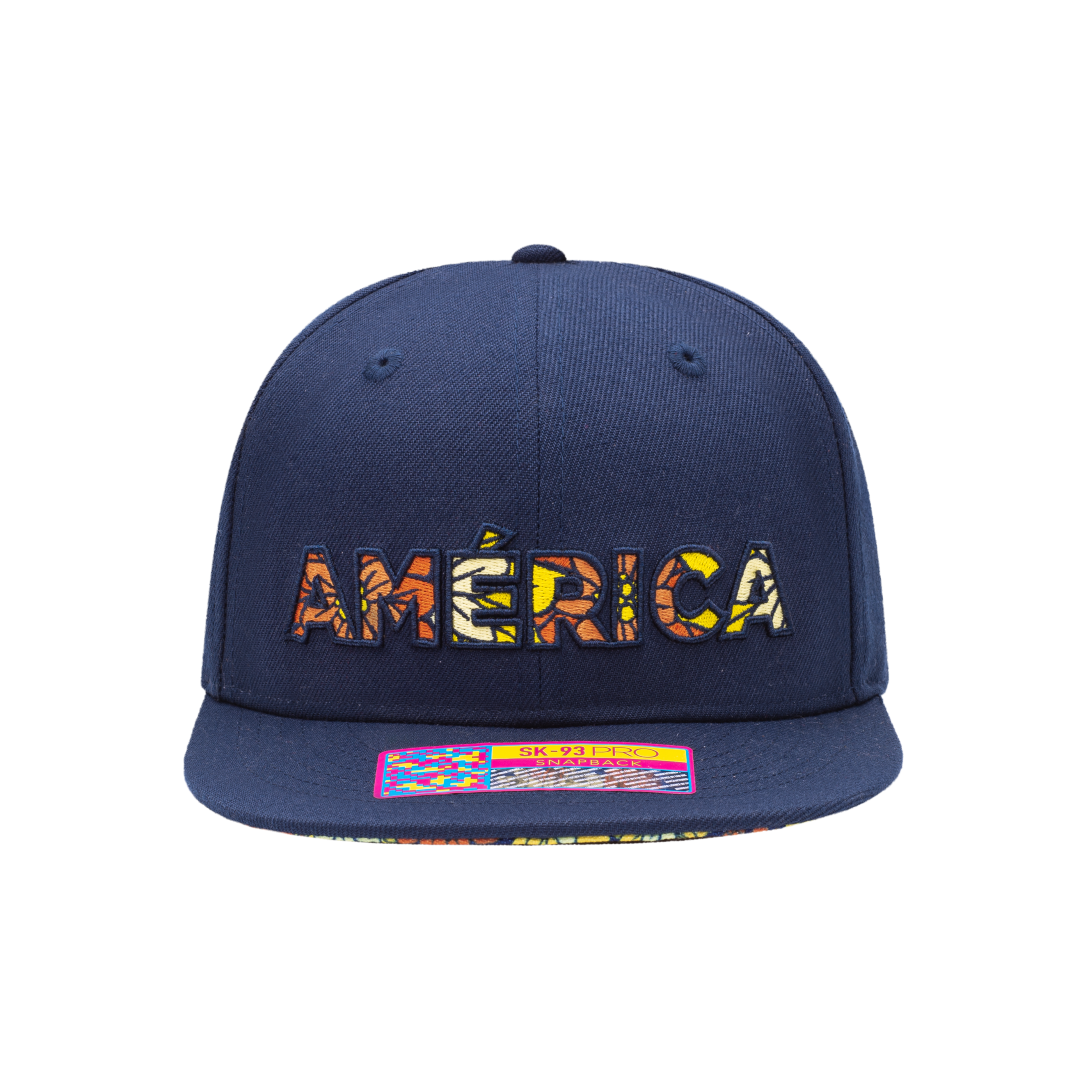 Club America Day of the Dead Snapback Hat with America script with marigold floral overlay embroidered on the front, Club America logo embroidered on the side, "Dia de Muertos" embroidered on the back, and marigold floral print on the under peak. The hat has a high crown, flat peak brim, and a snapback closure.